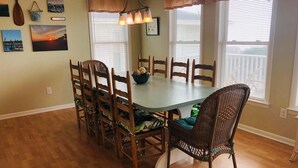 A dining room with a wooden table, chairs, and a wicker chair.