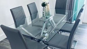 A conference table with six black leather chairs, a glass top, and a decorative vase with flowers.