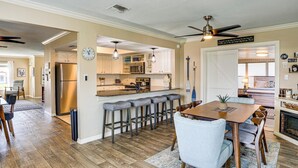 Una cocina moderna con una isla central, taburetes de bar y un comedor con una mesa y sillas de madera.