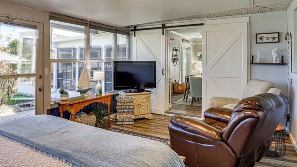 Una sala de estar acogedora con un televisor grande, un sillón de cuero y un aparador de madera con un letrero.
