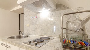 Una cocina con un lavaplatos de acero inoxidable, una estufa integrada y un escurreplatos con utensilios.