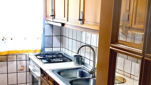 Una cocina con gabinetes de madera, estufa, pileta y lavavajillas.