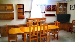 Un comedor con una mesa y sillas de madera, una chimenea y un televisor.