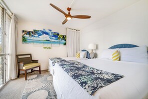 Una habitación de hotel con cama, una silla, un ventilador de techo y tres cuadros en la pared.