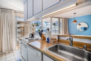Eine moderne Küche mit einem großen Fenster, einer Edelstahl-Spüle und einer Holz Arbeitsplatte.