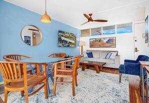 Una habitación con una mesa de comedor y sillas, un sofá, una pared azul y un ventilador de techo.