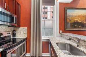 A kitchen with a stainless steel microwave, oven, and granite countertop.