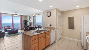 A modern kitchen with a central island, a dining area with a view, and a living room with a sofa and coffee table.