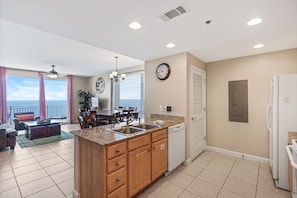 Una cocina moderna con una isla central, un comedor con vistas y una sala de estar con sofá y mesa de centro.