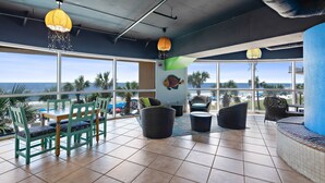 A spacious indoor area with large windows offering ocean views, a dining table with chairs, and various seating options.