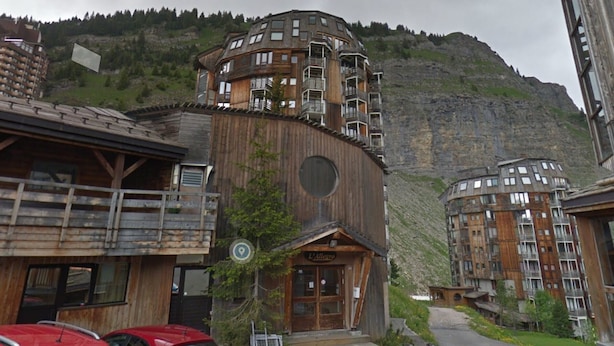 Un edificio in legno con balconi e uno sfondo montuoso.