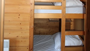 Camera con letto a castello, pareti in legno e materasso bianco sul letto superiore.