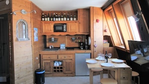 Una cucina compatta con mobili in legno, un forno a microonde, un lavello e un’area pranzo con tavolo e sedie.