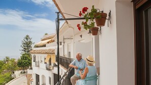 A balcony with a railing, a potted plant, and a person sitting on a chair. - Casa Mixa con Decoración Exclusiva, Estilo Industrial (Mijas)