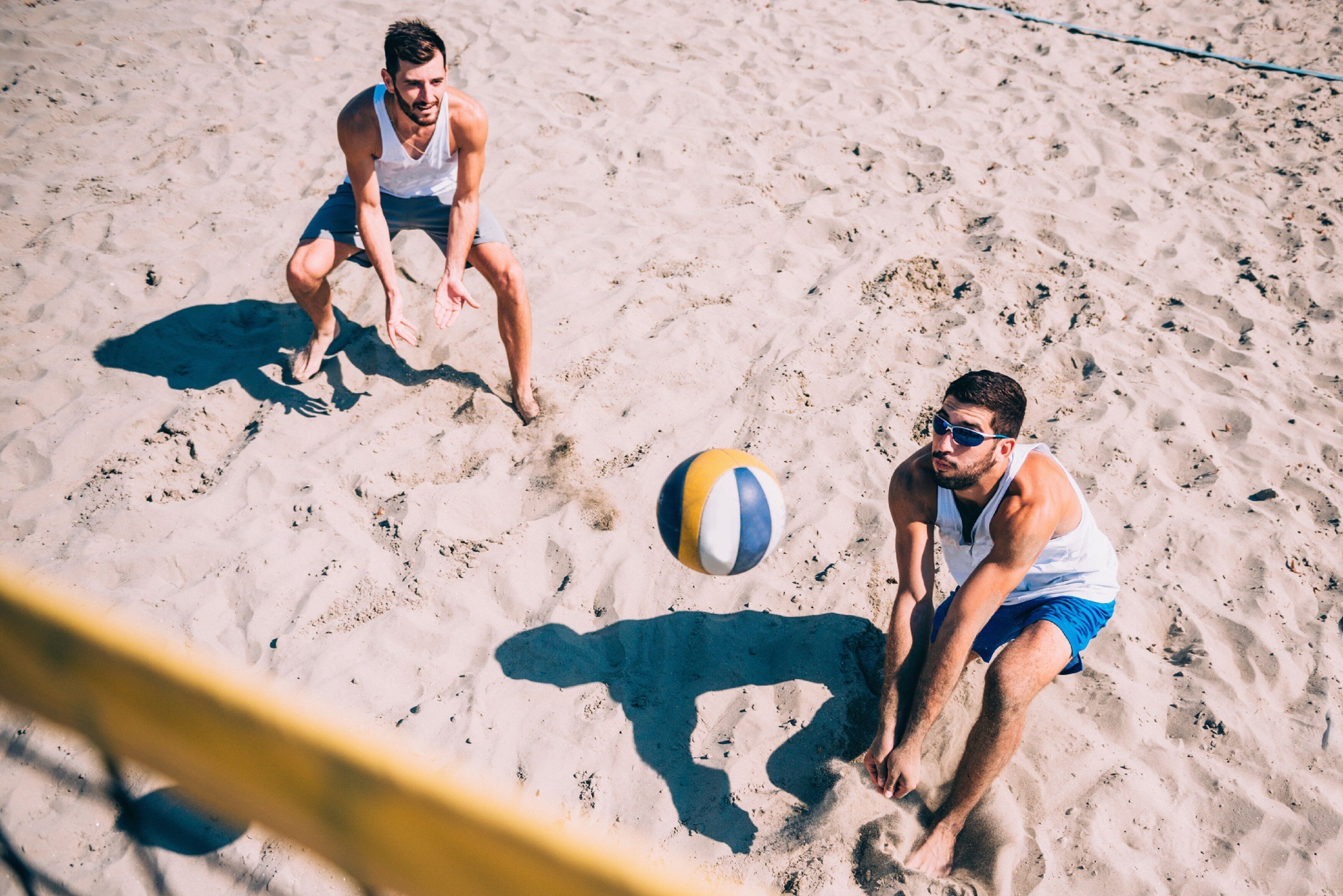 Deux personnes jouant au volleyball de plage sur une plage de sable.