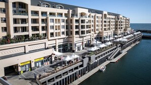 A multi-story hotel with balconies, a waterfront view, and outdoor seating areas. - Watercolours on Marina (Glenelg)