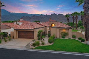 A residential property with a garage, a well-maintained lawn, and a mountain backdrop.