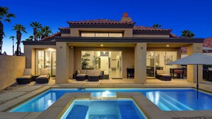 Una moderna casa a due piani con piscina, area salotto esterna e patio.