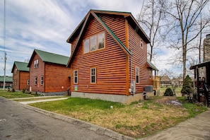A log cabin with a green roof, a stone foundation, and a small porch.