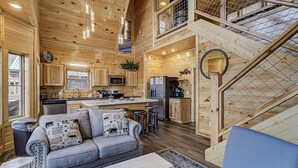 A spacious cabin with a kitchen, dining area, and a cozy living room with a sofa and a coffee table. - River View | Pigeon Forge  | Arcade | Hot Tub | WiFi | Fireplace (Pigeon Forge)