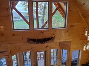 A cabin with multiple windows, a hanging canoe, and a deck area.