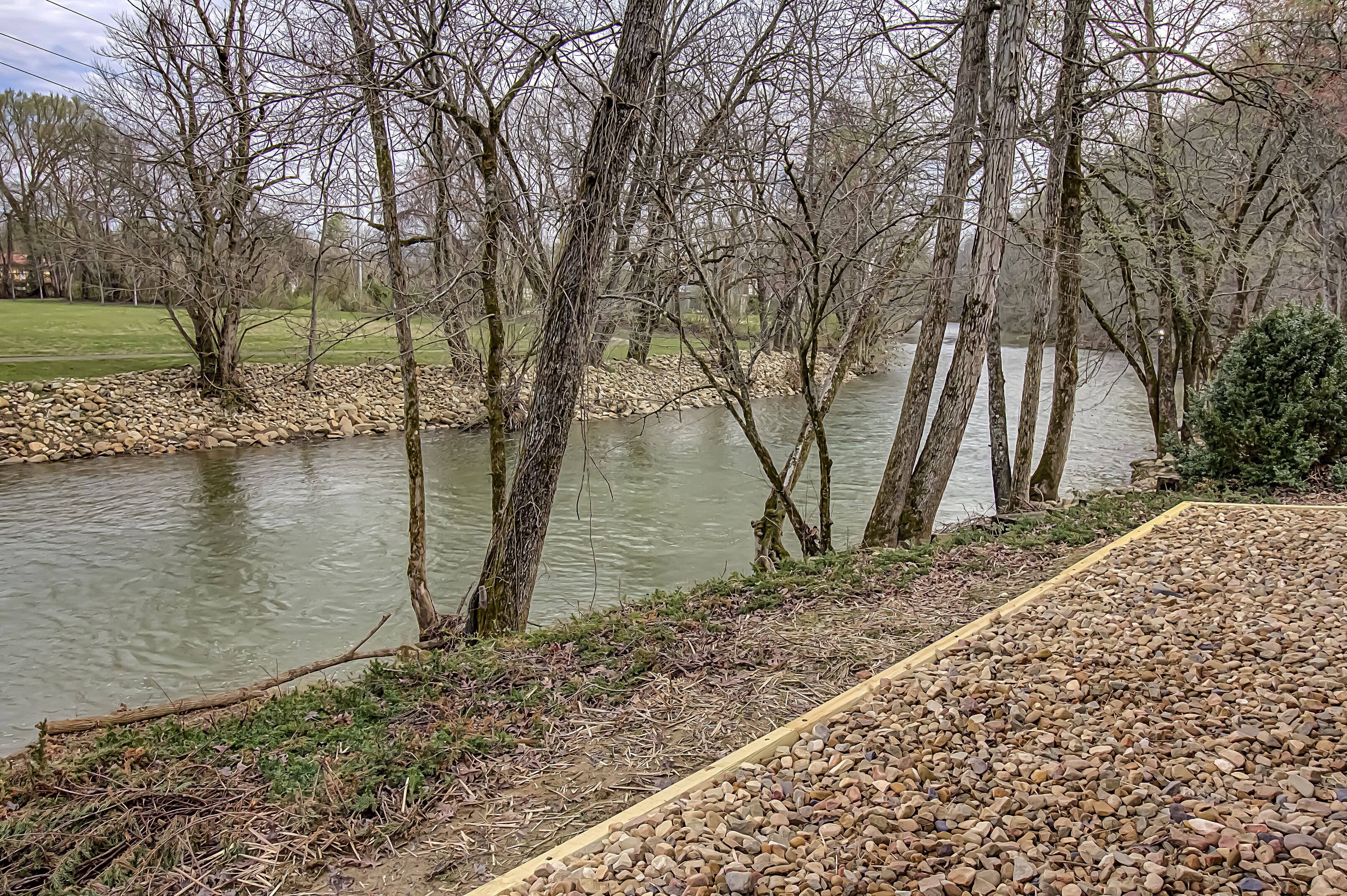 Une rivière bordée d’arbres et un sentier pavé de pierres.