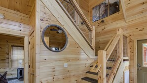 A wooden interior with a spiral staircase, a round mirror, and a door with a window. - River View | Pigeon Forge  | Arcade | Hot Tub | WiFi | Fireplace (Pigeon Forge)