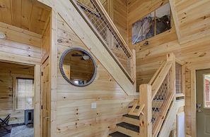 A wooden interior with a spiral staircase, a round mirror, and a door with a window.