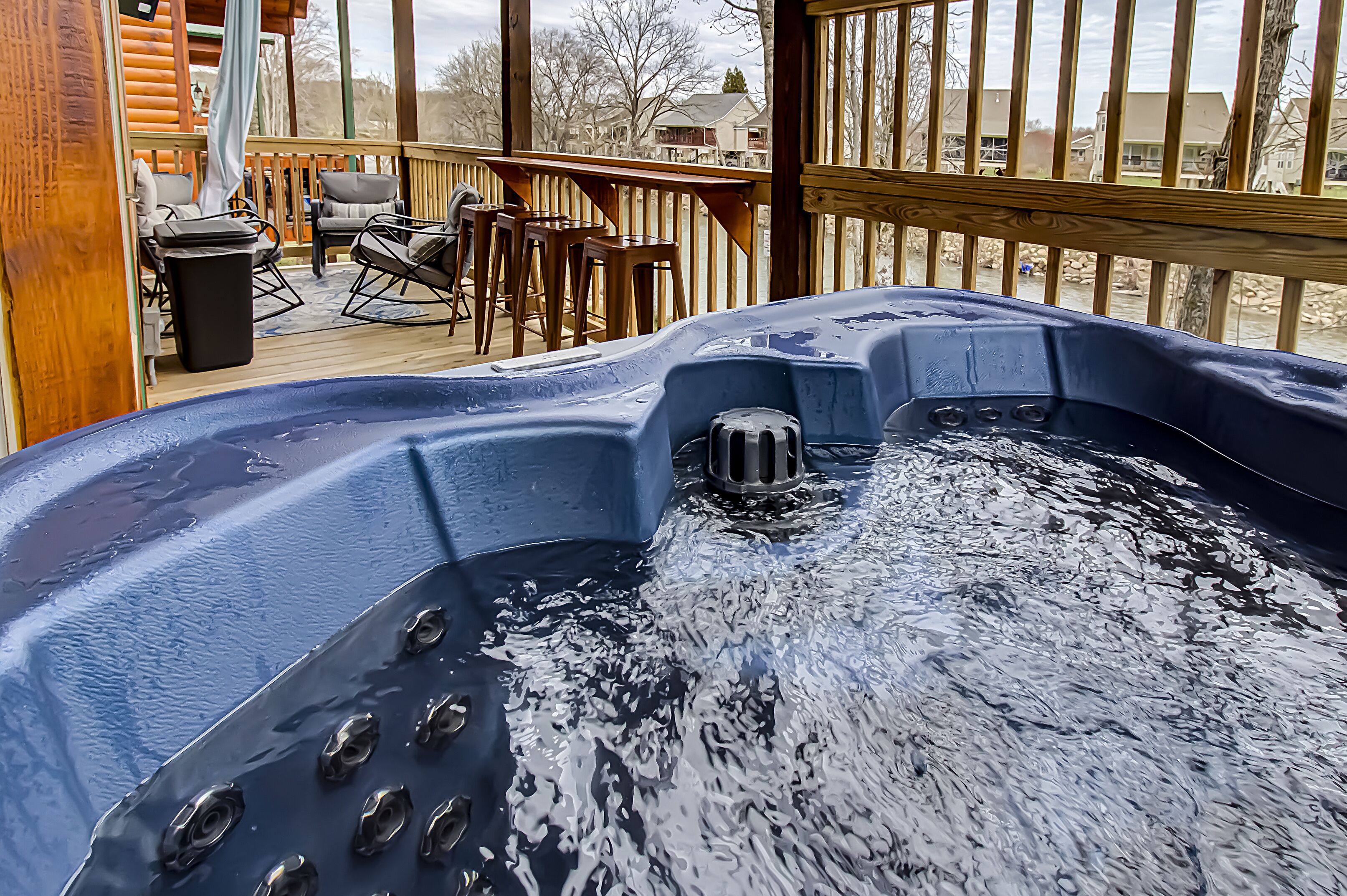 A hot tub on a wooden deck with a view of houses in the background.