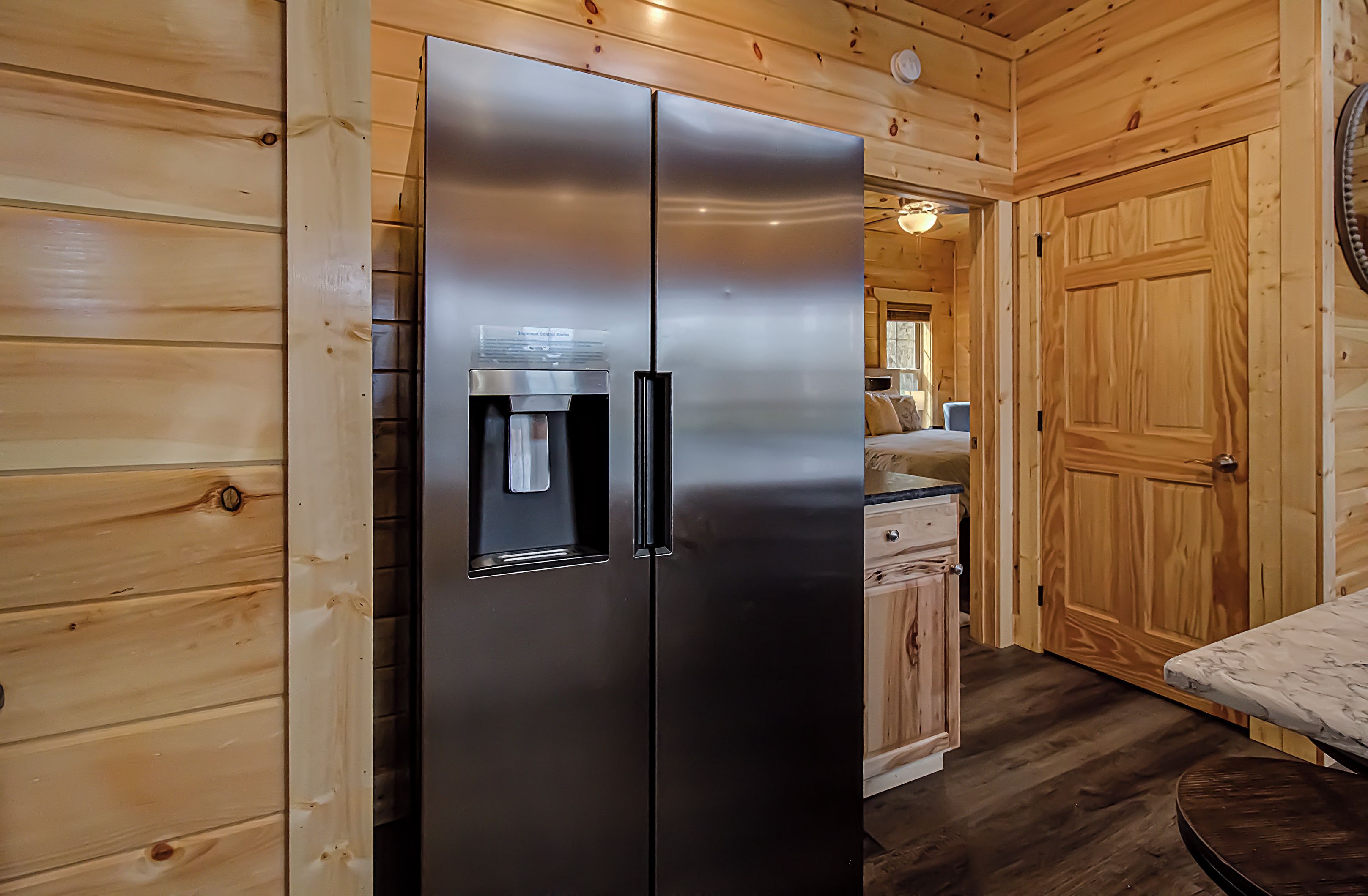 A modern kitchen with a stainless steel refrigerator, wooden cabinets, and a water dispenser.