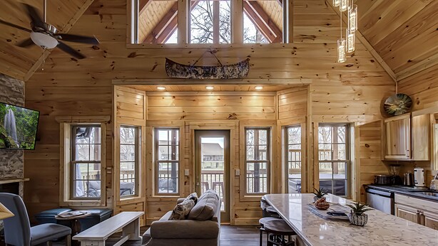 A log cabin interior with a dining area, kitchen, and seating space. - River View | Pigeon Forge  | Arcade | Hot Tub | WiFi | Fireplace (Pigeon Forge)