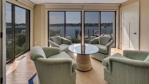 A balcony with a view of a body of water, furnished with green chairs and a round table. - Lake Charlevoix Views | Private Balcony | Pool, Hot Tub, Sauna (Charlevoix)