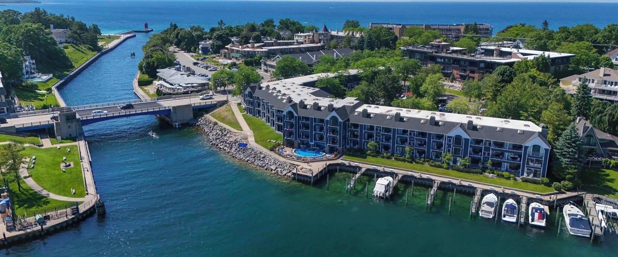A waterfront hotel with a large building, a bridge, and a marina with boats.