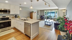 Une cuisine moderne avec des armoires blanches, des appareils en acier inoxydable et des luminaires suspendus.
