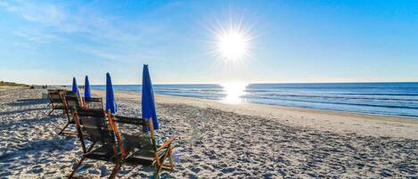Uma praia com guarda-sóis e espreguiçadeiras.