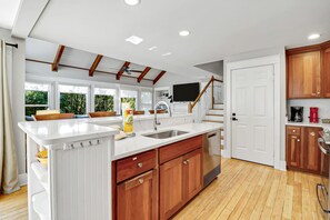 A modern kitchen with a large island, wooden cabinets, and a built-in stove.