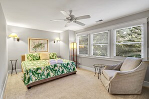 A bedroom with a bed, a chair, a ceiling fan, and a window with blinds.