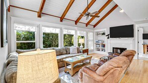 A spacious living room with a high ceiling, large windows, a fireplace, and a television. - Walk to Beach | Private Pool | Pet Friendly (Hilton Head Island)