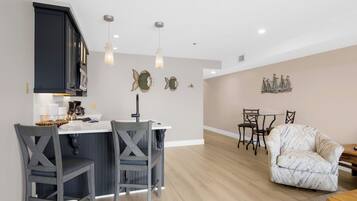 A modern kitchen with a central island, bar stools, and pendant lighting.