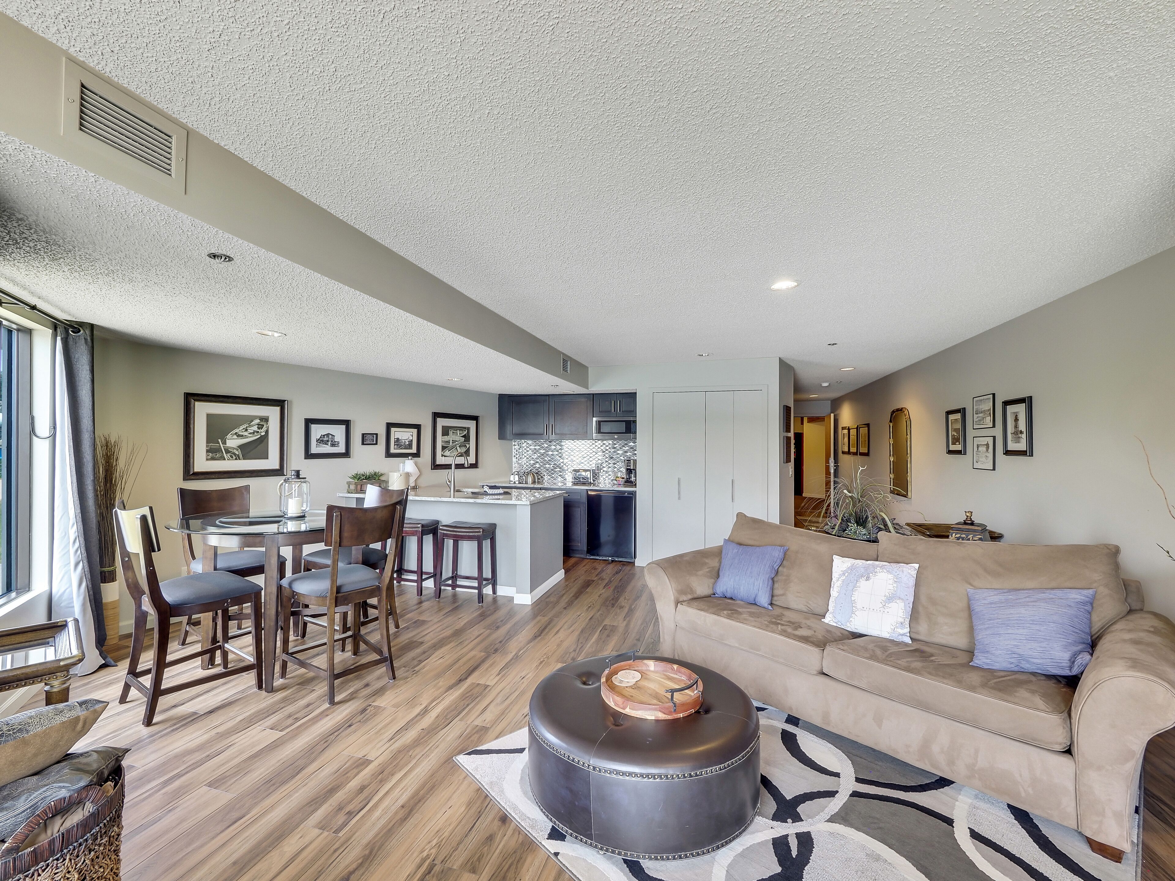 A spacious living area with a sofa, ottoman, and dining set.