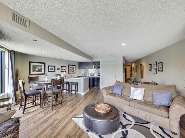 A spacious living area with a sofa, ottoman, and dining set.
