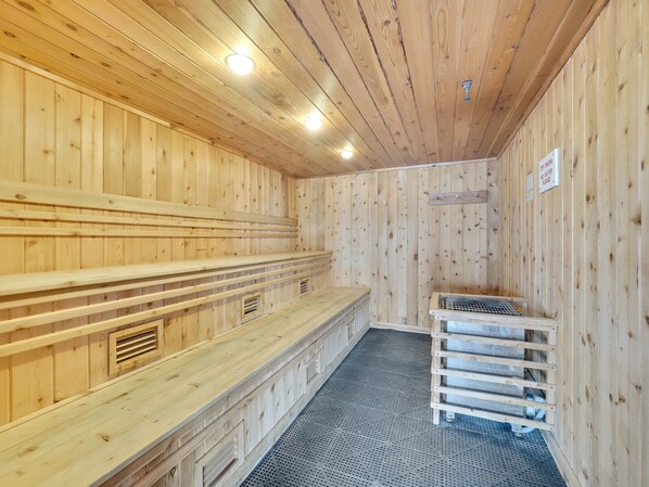 A sauna with wooden walls and benches, a metal grate, and a ventilation system.