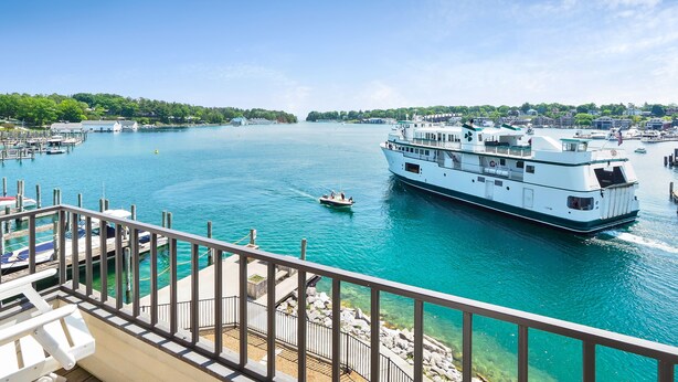 A large white riverboat docked at a marina with clear turquoise water, surrounded by docks and small boats. - EWI 222 | Downtown Charlevoix | Pool, Hot Tub, Sauna (Charlevoix)