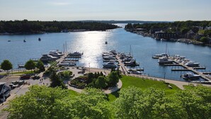 A marina with boats docked, a pedestrian walkway, and greenery. - EWI 222 | Downtown Charlevoix | Pool, Hot Tub, Sauna (Charlevoix)