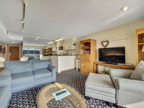 Un salon comprenant un canapé, des fauteuils, une table basse et un téléviseur.