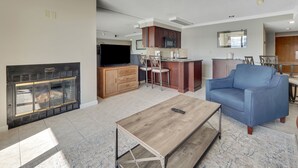 A modern living room with a fireplace, a television, and a blue armchair. - 223 Edgewater Inn | Pool, Hot Tub, Sauna | Cozy 1 BR Condo (Charlevoix)