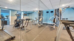 Une salle de sport équipée de tapis de course, de vélos elliptiques et d’appareils de musculation.