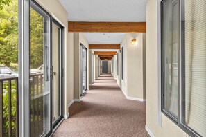 A corridor with glass doors, wooden beams, and a carpeted floor.