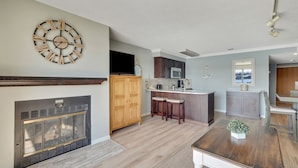 A modern kitchen with a central island, dark wooden cabinets, and a built-in microwave. - 227 Edgewater Inn | Private Lakefront Balcony | Pool, Hot Tub, Sauna (Charlevoix)