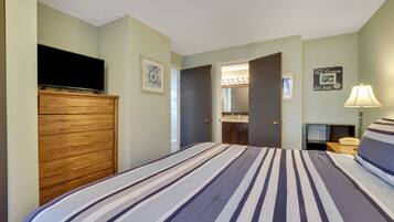 Habitación de hotel con una cama, un aparador de madera, un televisor, un baño con espejo y una pared con una frase motivacional.